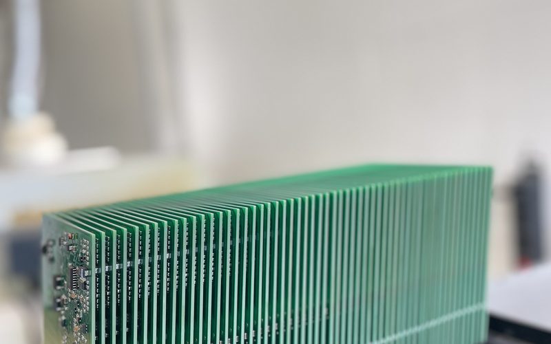 Stapel bestückter Leiterplatten in einem schwarzen Rack vor hellem Hintergrund